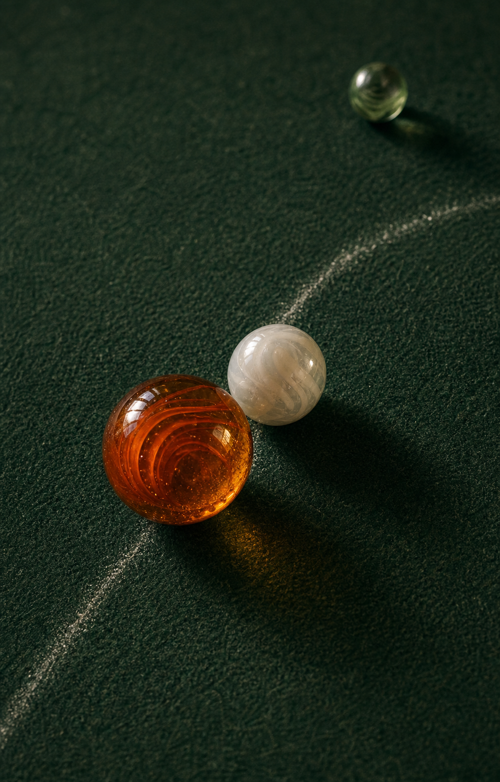 An orange shooter marble making a glancing hit on a white target marble